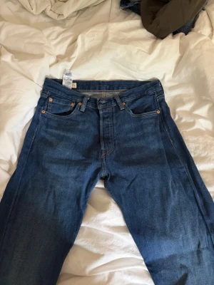 Levi's Premium raka blå jeans - Säljer ett par klassiska blå Levi's Premium jeans med rak passform och fem fickor. Jeansen har kopparfärgade nitar och kontrastsömmar. Tillverkade i slitstarkt denimtyg som ger en tidlös look. Perfekta till alla tillfällen och lätta att styla.