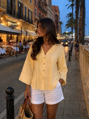 Ljusgul blus med vida ärmar från Zara - Ljusgul blus med v-ringning och knappar framtill. Blusen har vida trekvartsärmar och en avslappnad passform. Tillverkad i ett lätt tyg som passar perfekt för varma dagar. Enkel och stilren design som är lätt att matcha.