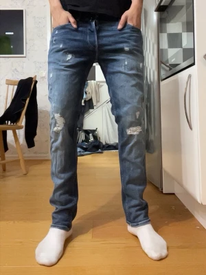 replay grover ( straight fit ) jeans - Säljer ett par blå skinny jeans med slitningar och hål på benen. Jeansen har klassisk femficksdesign, normalhög midja och är tillverkade i denim med stretch. Perfekta för en avslappnad och trendig look.
