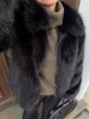 Svart fluffig  fuskpälsjacka med dragkedja - Säljer en svart, fluffig fuskpälsjacka med dragkedja framtill. Jackan har en bred krage och en lyxig, voluminös look. Perfekt för att hålla värmen och ge en trendig vibe till din outfit. Passar till dig som vill sticka ut i vintermörkret.