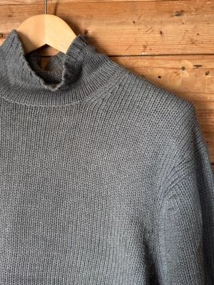Vintage Polo Jeans Co. Ralph Lauren stickad polotröja grå L - Vintage Polo Jeans Co. Ralph Lauren stickad tröja i grå 100 % bomull. Kraftigare stickning med hög mock neck/polokrage, ribbade avslut och vävd Polo Jeans Co.-patch framtill. Klassisk avslappnad 90s/Y2K-passform.  Fint vintagebruksskick med lätt naturligt slitage.  Storlek L | Made in Hong Kong Bröst 64 cm | Axel 50 cm | Ärm 67 cm | Längd 68 cm