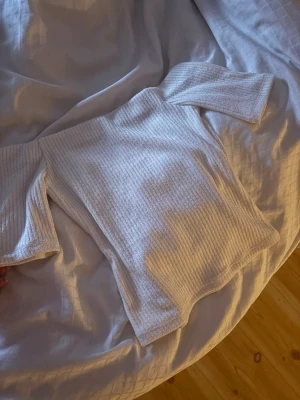 Vit ribbad offshoulder topp - Trendig vit ribbad topp med offshoulder-design och trekvartsärm. Perfekt för dig som vill ha en enkel men snygg topp till din garderob. Materialet är mjukt och stretchigt för en bekväm passform. Strl xs från hm, aldrig använt den