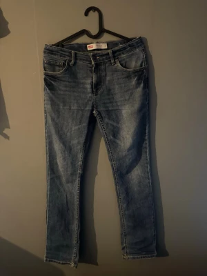 Levi's 511 Slim blå jeans - Säljer ett par klassiska Levi's 511 Slim jeans i blå denim. Modellen har smal passform, fem fickor och normal midja. Jeansen har snygga slitningar och kontrastsömmar. Perfekta för dig som gillar en tidlös och avslappnad stil. Dom är 14a och är 164 cm långa. /Hör av er vid frågor eller pris👌😃