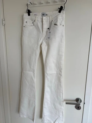 Vita bootcut jeans med full längd - Säljer ett par vita bootcut jeans i full längd. Jeansen har klassisk femficksdesign, raka ben med lätt utsvängning nedtill och stängs med knapp och dragkedja. Perfekta för dig som vill ha en clean och fräsch look till vardags.