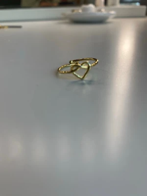 Guldfärgad ring med hjärtdetalj - Söt och stilren ring i guldfärg med en öppen hjärtformad detalj framtill. Man kan justera efter hur sitt finger ser ut