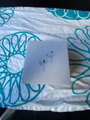 Vita trådlösa in-ear hörlurar - Säljer ett par vita trådlösa in-ear hörlurar i stilren design. Kommer i originalförpackning med minimalistiskt tryck på framsidan. Perfekta för dig som vill ha smidiga och snygga hörlurar till mobilen eller datorn.