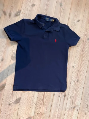 Ralph lauren pike -  Mörkblå Ralph lauren piké i nyskick Inköpt i våras för 1399 och säljer den då den tyvär inhe passar. Den är mycket sparsamt andvänd och är ungefär som ny. Inga defekter eller hål osv. Priset är inte hugged i sten så tveka inte att höra av dig vid minsta fundering.
