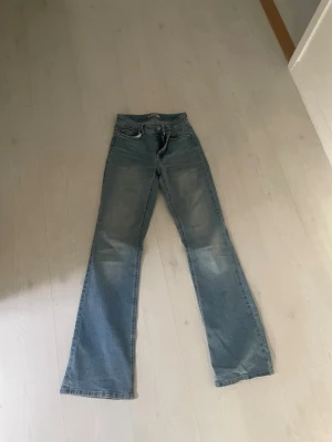 Ljusblå bootcut jeans från ONLY - Säljer ett par ljusblå bootcut jeans från ONLY med klassisk femficksmodell och dragkedja. Jeansen har en något utsvängd passform nedtill och är tillverkade i denim med lätt tvättad look. Perfekta för en avslappnad och trendig stil.