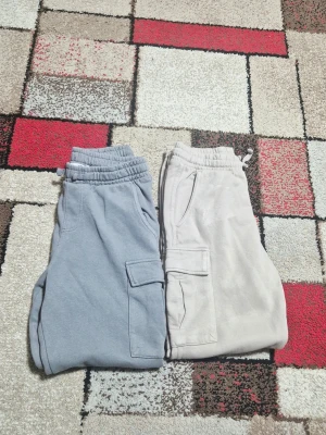 Två par mjukisbyxor med cargofickor - Säljer två par mjukisbyxor, ett par i ljusblått och ett par i beige. Båda har elastisk midja med dragsko, sidofickor och praktiska cargofickor på benen. Perfekta för en avslappnad och chill stil.storlek 150