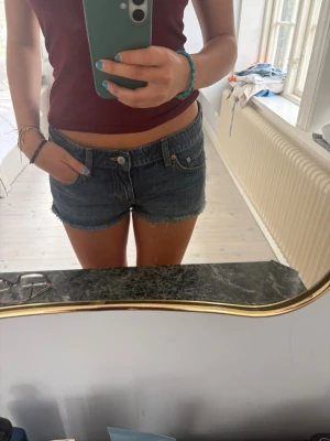 Lågmidjade jeansshorts i blå denim - Säljer ett nästan oanvända💕  par klassiska blå jeansshorts med låg midja och råa kanter. Shortsen har fem fickor och knappgylf. Perfekta för varma dagar och ger en avslappnad vibe. Dom e skitsnygga men måste rensa ut det som jag inte använder!😇Köpte för 400. Endast använt max två gånger. Pris kan diskuteras 