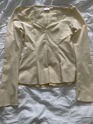 Ljusbeige v-ringad blus - Snygg ljusbeige blus med v-ringning och figurnära passform. Blusen har långa ärmar och en lätt utsvängd nederkant. Tillverkad i ett mjukt tyg som ger en elegant känsla. Perfekt att styla med jeans eller kjol.