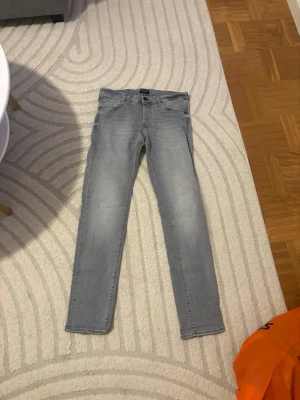 Ljusgrå skinny jeans Jack & Jones - Säljer ett par ljusgrå skinny jeans från Jack & Jones. Jeansen har klassisk femficksdesign, bälteshällor och knappgylf. Snygg tvättad look och smal passform som sitter tajt längs benen. Perfekta till en avslappnad streetstil.