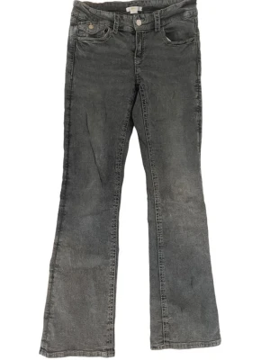 Grå bootcut jeans med fickor - Ett par grå bootcut jeans med klassisk femficksdesign och knappgylf. Jeansen har utsvängda ben och bakfickor med lock och knapp. Tillverkade i denim med en tvättad look som ger en avslappnad vibe.