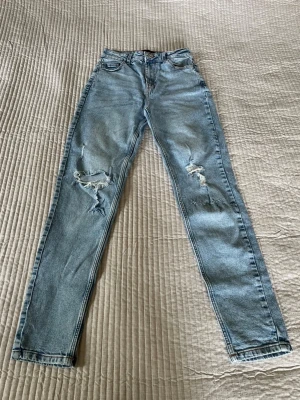 Ljusa jeans från PIECES - Säljer ett par ljusblå jeans från PIECES i storlek S. Modellen är skinny fit med hög midja och slitningar på båda benen för en trendig, avslappnad look. Passar till allt 