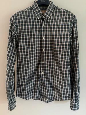 Scotch & Soda rutig skjorta M - Snygg rutig skjorta från Scotch & Soda i storlek M. Mörkblå grundfärg med tunna streck i vitt, blått och ljusgult. Vita knappar och klassisk passform. 100% bomull. Mycket bra skick, utan skador eller annat.