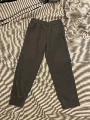 Mörkgrå mjukisbyxor i fleece - Mysiga mörkgrå mjukisbyxor från Wear i mjuk fleece. Byxorna har resår i midjan och muddar vid bensluten för extra komfort. Perfekta för chill dagar hemma eller när du vill vara extra bekväm.