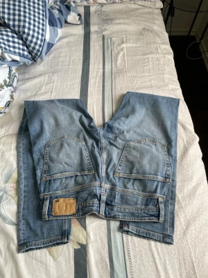 Ljusblå och grå Slimfit jeans med bakfickor - Säljer ett par ljusblå och ett par grå jeans med raka ben och klassisk femficksdesign. Jeansen har två stora bakfickor och en patch vid linningen bak. Materialet är denim i bomull och passformerna är Slimfit. Perfekta för en casual look.