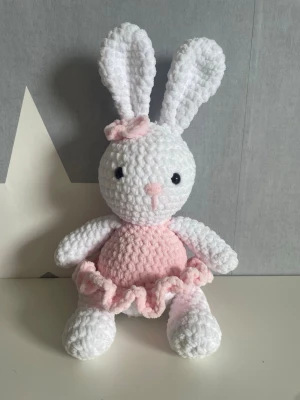 Virkad kanin i rosa klänning - Supergullig handvirkad kanin i mjukt vitt garn med rosa klänning och rosett på ena örat. Kaninen har svarta ögon, rosa nos och detaljer, samt långa öron. Perfekt som dekoration eller present. Vid frågor hör gärna av dig 