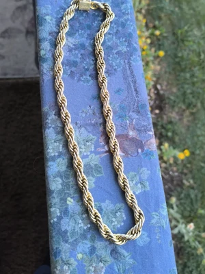 Tjockt tvinnat guldfärgat halsband - Säljer ett snyggt halsband i guldfärg med tvinnad kedja som ger en chunky och trendig look. Halsbandet har en klassisk låsning och passar perfekt för dig som vill sticka ut med accessoarerna. Materialet ser ut som metall med guldfinish.