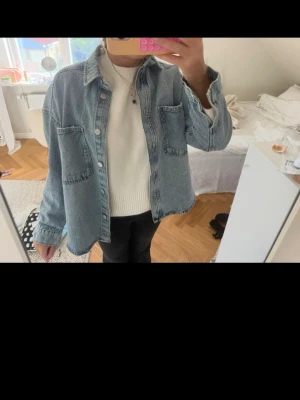 Ljusblå  jeansjacka - Säljer en ljusblå oversized jeansjacka med två stora bröstfickor och klassisk krage. Jackan har knappstängning framtill och raka ärmar. 