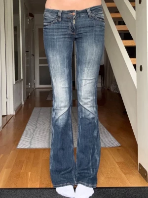 Blå lågmidjade bootcut weekday jeans - Säljer ett par blå bootcut jeans med tvättade detaljer. Jeansen har klassisk femficksmodell, låg midja och utsvängda ben. Perfekta för dig som gillar en retro och avslappnad stil. innerbenslängd 85 cm, jag är 175/176 för referens. den stora gröna lappen på baksidan är bort sprättad, men inga defekter. pris går att diskuteras!