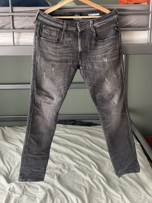 Grå slitna jeans med raka ben - Säljer ett par grå jeans med slitningar och raka ben. Jeansen har fem fickor, tydliga sömmar och en tvättad look. Passar dig som gillar en avslappnad och trendig stil. Materialet är denim med stretch. Har ett litet hål men går lätt att sy ihop priser kan diskuteras 