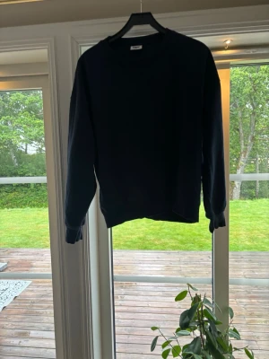 Mörkblå basic sweatshirt - En enkel mörkblå sweatshirt med rund hals och långa ärmar. Tröjan har ribbade muddar vid ärmslut och nederkant, perfekt för en avslappnad och stilren look. Passar till det mesta och är ett måste i garderoben.
