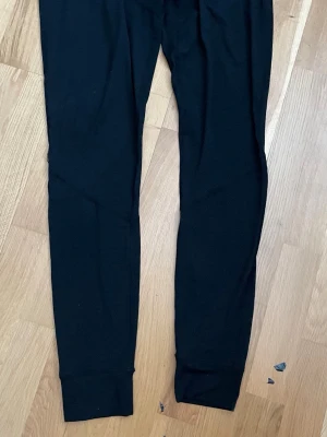 Svarta träningslegging , Everest, L - Ett par svarta leggings med smal passform och bred mudd vid benslut. Tillverkade i ett mjukt och stretchigt material som sitter skönt mot kroppen. Perfekta att matcha med oversized tröjor eller hoodies.