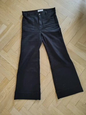 St. Monica Highrise från Jeanerica - Säljer ett par svarta jeans från Jeanerica, modell St. Monica high rise SW006 Rinse Stay Black. Jeansen har hög midja, raka och utsvängda ben samt stora fickor fram. Materialet består av ekologisk bomull, återvunnen polyester och elastan för extra stretch.