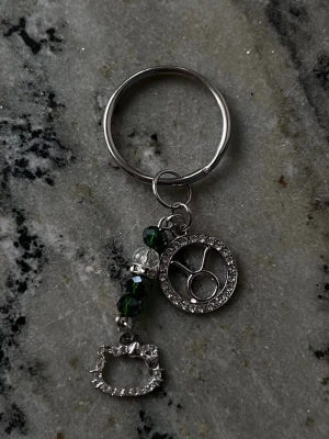 Nyckelring Oxe/Taurus + Hello Kitty♉︎ - Handgjord nyckelring med stjärntecknet Oxe. Mörkgröna akrylpärlor för att symbolisera Oxens birthstone Emerald. Och en Hello Kitty charm!
