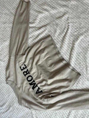 Beige stickad tröja - Beige stickad tröja från Gina tricot med texten amore.Nytt skick och inte synligt andvänd.