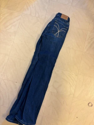 Blå bootcut jeans med broderade fickor - Säljer ett par blå bootcut jeans med snygga broderade detaljer på bakfickorna. Klassisk femficksmodell med bälteshällor och normal midja. Jeansen är i ett mjukt denimtyg som passar perfekt till en avslappnad stil. Från Bubbleroom. Storlek 36. Perfekt längd på mig som är 1,68. Använda fåtal gånger. 