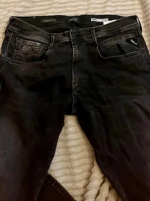 Svarta Replay slim fit jeans storlek Mycket bra skick! Syrlk 34/32 - Snygga svarta jeans från Replay i slim fit-modell. Jeansen har klassisk femficksdesign, svarta sömmar och diskreta slitningar för en cool look. Tillverkade i stretchigt denim för extra komfort. Perfekta till en avslappnad streetstyle.