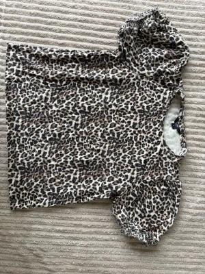 Leopardmönstrad topp med puffärm - Snygg topp med leopardmönster och puffiga korta ärmar. T-shirten har rund halsringning och är tillverkad i mjukt material som känns skönt mot huden. Perfekt för dig som vill sticka ut lite extra.