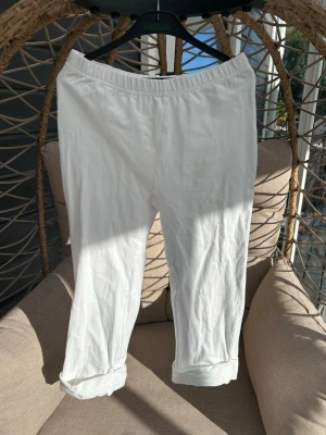 Leggings strl. 134 - Säljer ett par vita leggings med resår i midjan och uppvikta benslut. Byxorna är tillverkade i ett lätt och luftigt material, perfekta för varma dagar. 