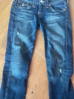 True Religion jeans blå - Snygga blå jeans från True Religion, blåa med fikor där bak och slitningar på framsidan 