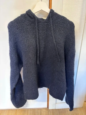 Mörkgrå stickad hoodie - Mysig marinblå stickad hoodie med luva och dragsko. Tröjan har en avslappnad passform, långa ärmar och är tillverkad i ett fluffigt, mjukt material som känns skönt mot huden. Perfekt för kyliga dagar när du vill vara både bekväm och snygg. Är från Gina tricot i stl M. Inga defekter eller liknande. Bara att höra av dig vid frågor eller fler bilder!💕