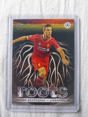Fotbollskort Jordan Henderson Roots - Samlarobjekt: ett fotbollskort från Topps 'Roots'-serie med Jordan Henderson i Liverpool FCs röda matchställ. Kortet har tryck på både fram- och baksida och är skyddat i plastficka. Perfekt för dig som gillar fotboll och samlarkort.