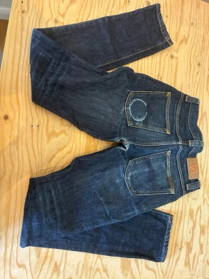 Mörkblå raka jeans med patch - Säljer ett par mörkblå nudie jeans. Modell grim Tim. Hör av dig vid frågor priset är inte satt i sten.