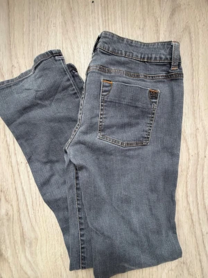 Low rise bootcut y2k jeans - Snygga grå dc jeans i bootcut-modell low rise  med klassiska fem fickor och kontrastsömmar. Jeansen har bälteshällor, knappgylf och dekorativa knappar vid ena fickan. Materialet är mjukt denim som ger en avslappnad look. Y2k stil 