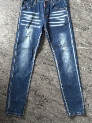 Blå slitna skinny jeans med detaljer - Säljer ett par blå skinny jeans med slitningar och ljusa tvättade detaljer på framsidan. Jeansen har klassisk femficksmodell och raka ben. Snygga kontrastsömmar och coola slitningar ger en trendig look. Perfekta för dig som gillar streetstyle.
