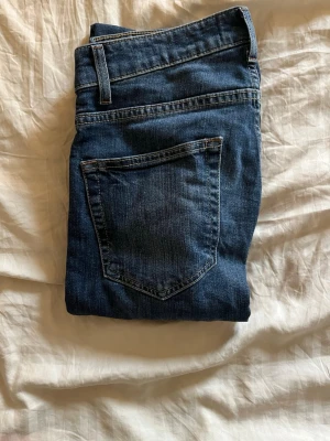 Mörkblå raka jeans - Säljer ett par klassiska mörkblå jeans med rak passform och fyra fickor. Jeansen har normal midja och är tillverkade i ett slitstarkt denimtyg. Perfekta för en avslappnad och tidlös look.