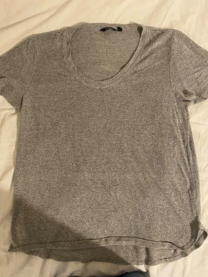 Grå basic t-shirt med rund hals - En enkel och mjuk grå t-shirt med rund halsringning och korta ärmar. Perfekt till jeans eller shorts för en avslappnad look. Tillverkad i ett tunt och bekvämt material som känns skönt mot huden.