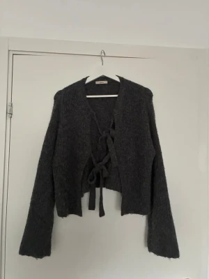Grå fluffig kofta med knytning - Mysig grå kofta från Gina tricot i fluffigt material. Koftan har långa ärmar, vanlig passform och knytning framtill som ger en trendig look. Perfekt för lager på lager och att styla med jeans eller kjol.