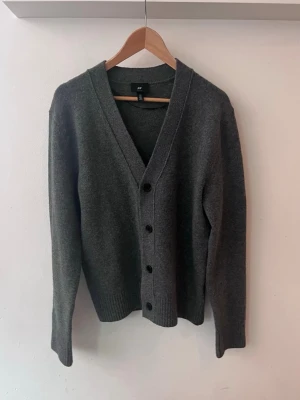 Grå Kofta Svarta Knappar - Säljer denna kofta från H&Ms manavdelning med knappar och en v-ringnad hals. Skulle säga att koftan är unisex då jag tycker den passar mig fint som tjej. Använd endast ett fåtal gånger (1-2 ggr). 