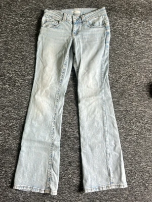 Ljusblå bootcut jeans - Säljer ett par ljusblå bootcut jeans med klassisk femficksdesign och normal midja. Jeansen har en snygg tvättad look och är tillverkade i ett mjukt denimtyg med lite stretch. Perfekta för en avslappnad och trendig stil. Säljer pga för stora och nästan aldrig använda ☺️