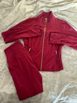 Vinrött träningsset från Lululemon - Säljer mitt superfina lululemon-set i färgen Red Merlot 🍷 Består av Define Jacket Luon med gulddragkedja + matchande leggings.  ✨ Endast testad en gång ✨ Nyskick, inga fläckar eller skador ✨ Den eftertraktade Red Merlot-färgen ✨ Jacka: storlek 12 (men är mer som en 10 slimfit) ✨ Byxor: storlek 8 ✨ Säljes som set  Perfekt för både träning och vardagslook! 🫶🏼
