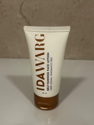 Ida Warg Self-Tanning Face Lotion - Brun utan sol-kräm för ansiktet från Ida Warg. Tuben är vit med bronsfärgat lock och text. Produkten är vegansk, parfymfri och ger en solkysst ton på bara några timmar. Innehåller 50 ml och passar alla hudtyper. använd två gånger. 