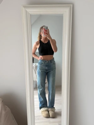 Svart ribbad crop top från Zara - Säljer en svart ribbad crop top från Zara. Modellen är ärmlös med breda axelband och rundad halsringning. Perfekt att styla till jeans eller kjol för en enkel och snygg look.