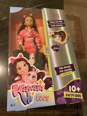 Kawaii Hi Lucy docka med tillbehör - Säljer en Kawaii Hi Lucy docka med långt brunt hår, rosa kläder och flera tillbehör som hårspännen, kam, ryggsäck och en liten figur. Perfekt för dig som gillar att styla hår och packa väskor. Kommer i originalförpackning med överraskningar.